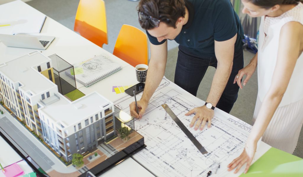 Architects drafting blueprint in office
